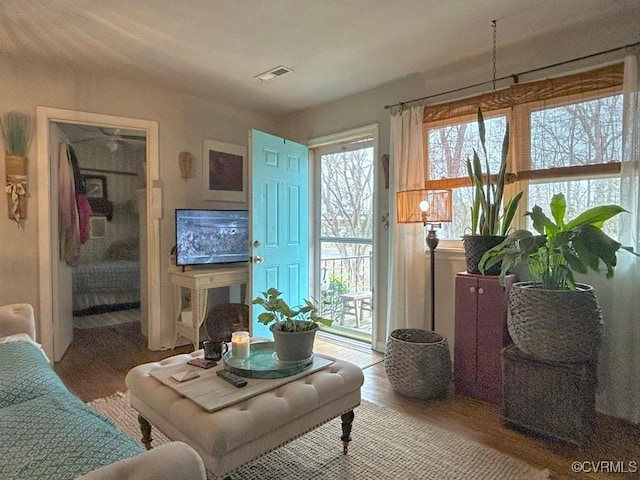 living area featuring visible vents and wood finished floors