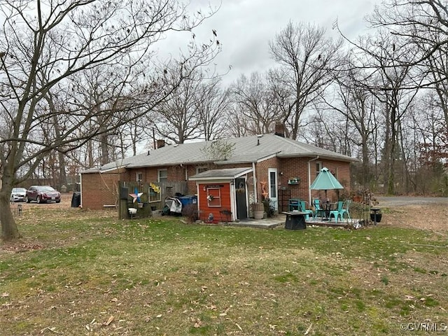 rear view of property with a lawn, brick siding, and a chimney