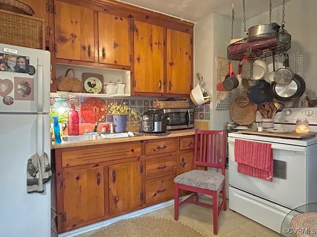 kitchen with a sink, white appliances, brown cabinetry, and light countertops