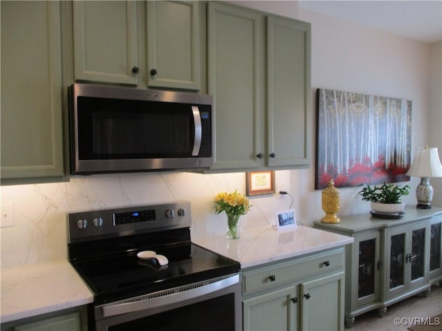 kitchen featuring stainless steel appliances, tasteful backsplash, and light stone counters