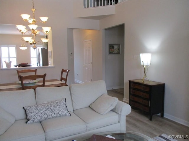 living room featuring a chandelier, light wood-style flooring, and baseboards