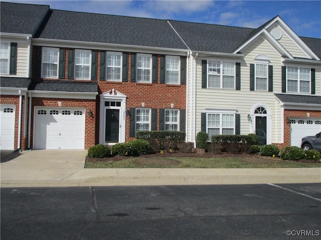 multi unit property with a garage, brick siding, driveway, and a shingled roof