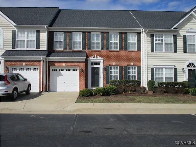 townhome / multi-family property with a shingled roof, brick siding, driveway, and an attached garage