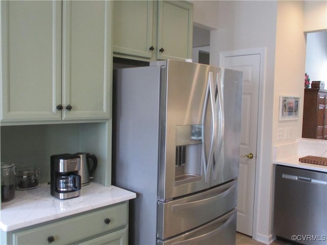 kitchen featuring stainless steel appliances, green cabinetry, and light stone countertops