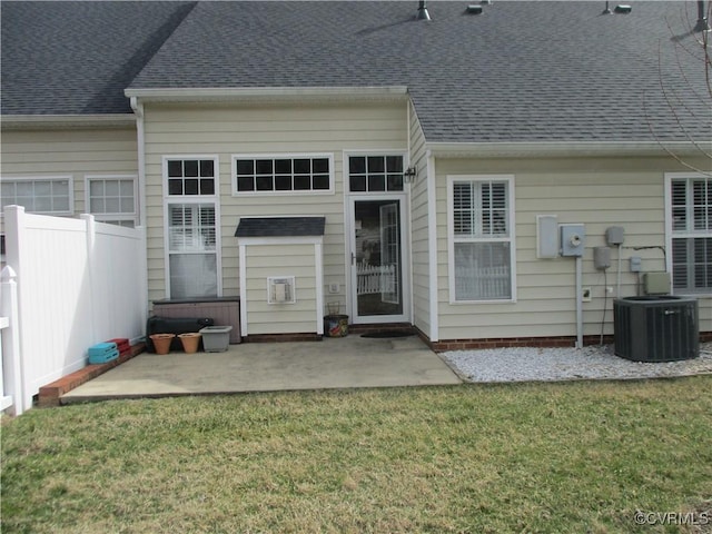 rear view of house featuring a yard, central air condition unit, a shingled roof, a patio area, and fence