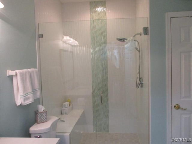 bathroom featuring tiled shower and toilet