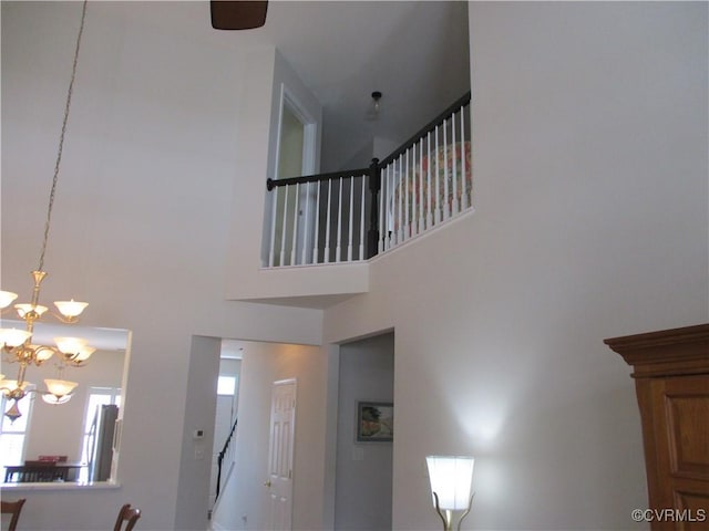 stairway featuring a towering ceiling and a notable chandelier