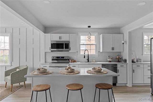 kitchen with stainless steel appliances, a breakfast bar, a wealth of natural light, and a sink