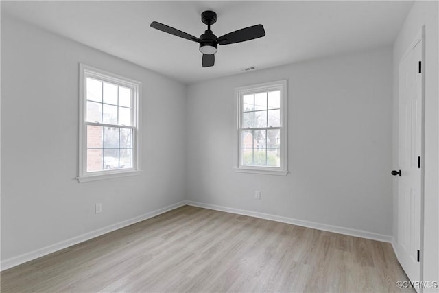 spare room featuring baseboards, visible vents, plenty of natural light, and light wood finished floors