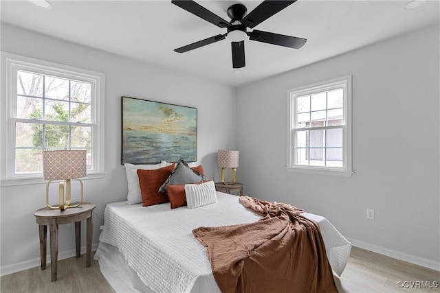 bedroom with light wood-style floors, multiple windows, and baseboards