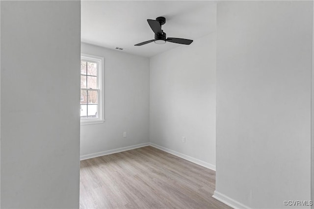 empty room with ceiling fan, wood finished floors, visible vents, and baseboards