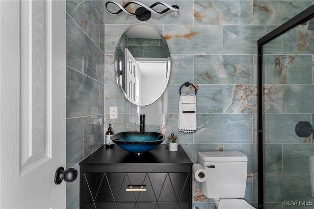 bathroom with toilet, backsplash, vanity, and tile walls