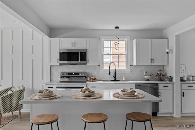 kitchen featuring white cabinets, a breakfast bar area, stainless steel appliances, and a sink