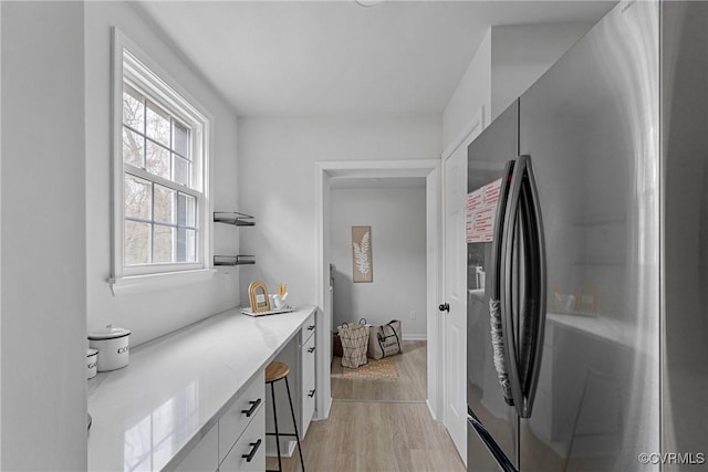 kitchen with light wood-style floors, white cabinetry, refrigerator with ice dispenser, and open shelves