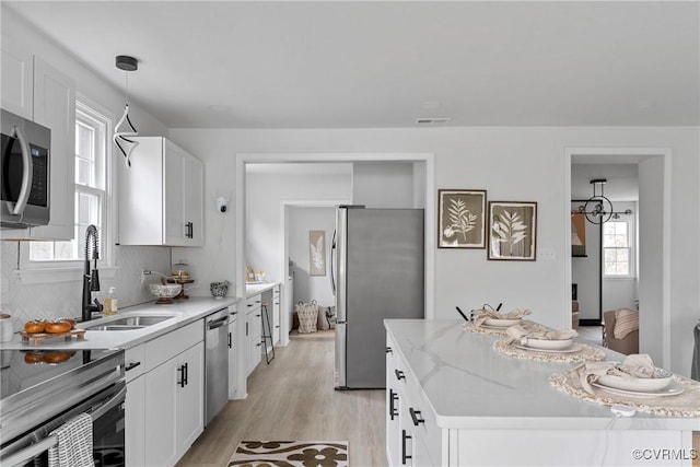 kitchen with a center island, stainless steel appliances, visible vents, light wood-style flooring, and a sink