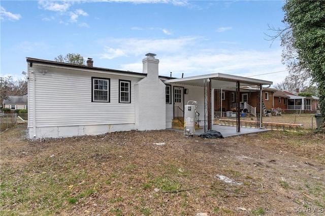 back of property with a chimney and fence