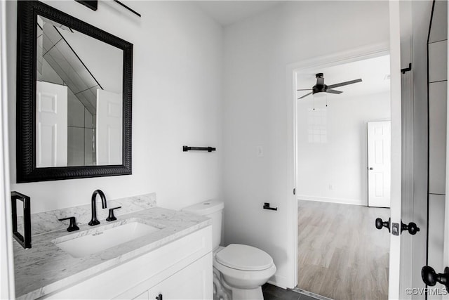 bathroom featuring ceiling fan, toilet, wood finished floors, vanity, and baseboards