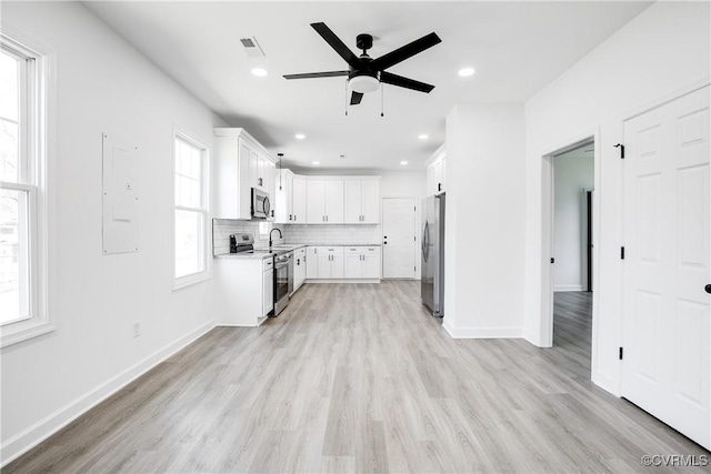 kitchen with stainless steel appliances, light countertops, visible vents, backsplash, and light wood-style floors