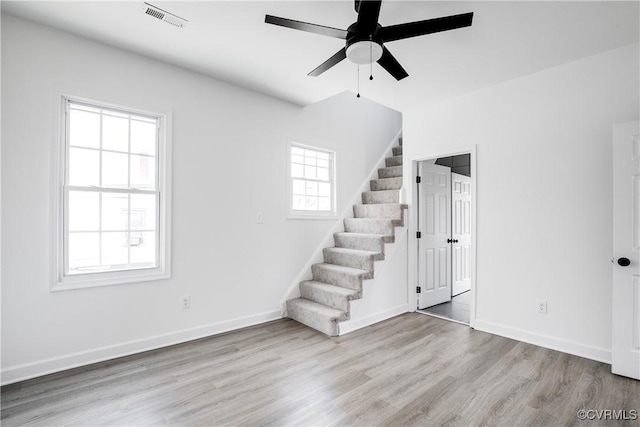 spare room featuring stairs, wood finished floors, visible vents, and baseboards