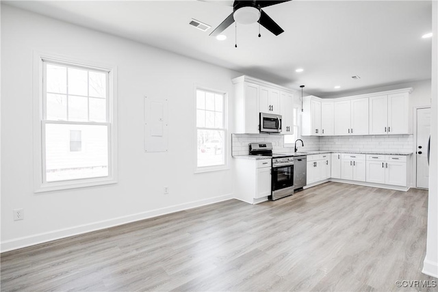 kitchen with visible vents, light wood-style flooring, backsplash, appliances with stainless steel finishes, and white cabinets