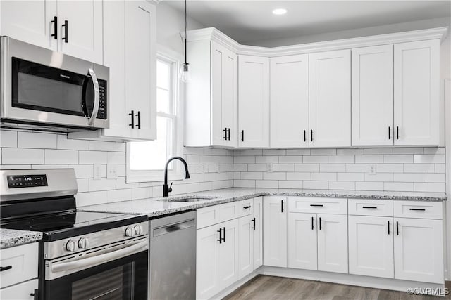 kitchen featuring light wood-style flooring, a sink, white cabinets, appliances with stainless steel finishes, and backsplash