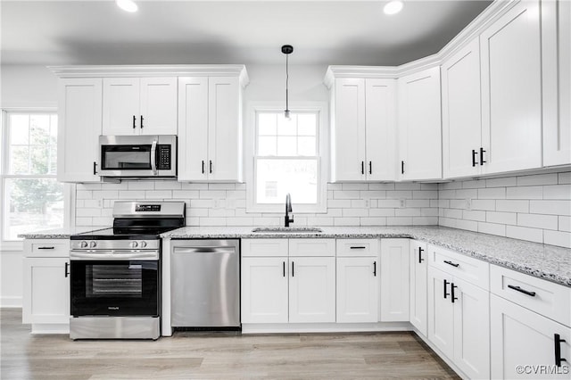 kitchen featuring stainless steel appliances, light wood-type flooring, a sink, and white cabinets