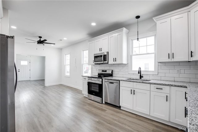 kitchen featuring appliances with stainless steel finishes, plenty of natural light, a sink, and decorative backsplash