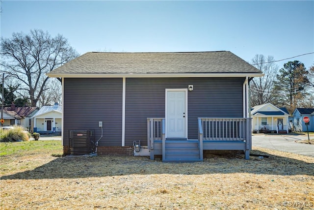 back of house featuring a shingled roof and cooling unit