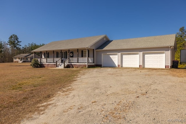 ranch-style house featuring a garage, a front yard, covered porch, and dirt driveway