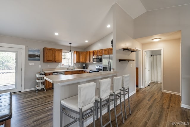 kitchen with lofted ceiling, stainless steel appliances, light countertops, dark wood-style floors, and brown cabinetry