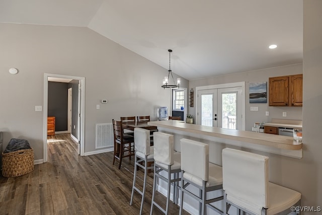 kitchen with lofted ceiling, a kitchen bar, brown cabinets, and dark wood-type flooring