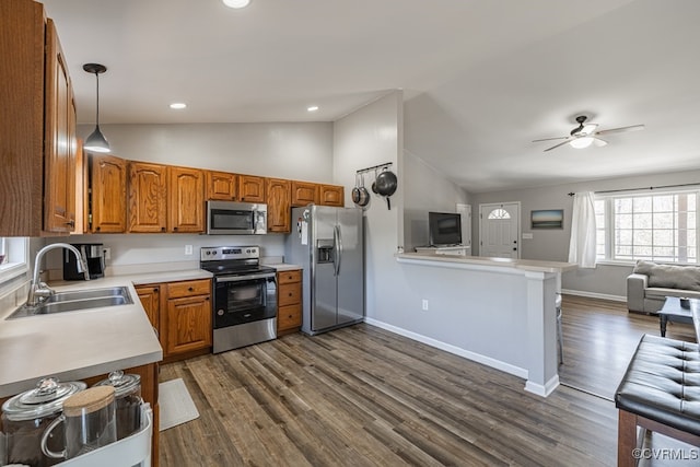 kitchen featuring light countertops, appliances with stainless steel finishes, brown cabinetry, open floor plan, and a sink