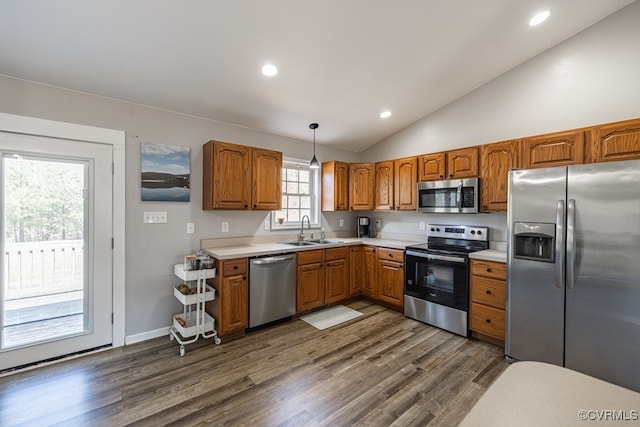 kitchen featuring stainless steel appliances, dark wood-style flooring, a sink, light countertops, and brown cabinetry