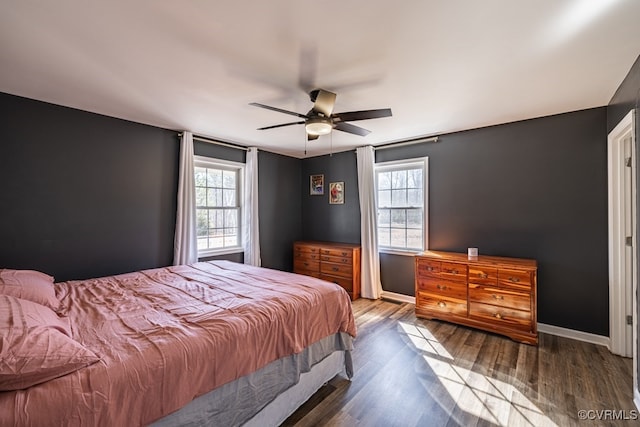 bedroom with ceiling fan, multiple windows, wood finished floors, and baseboards