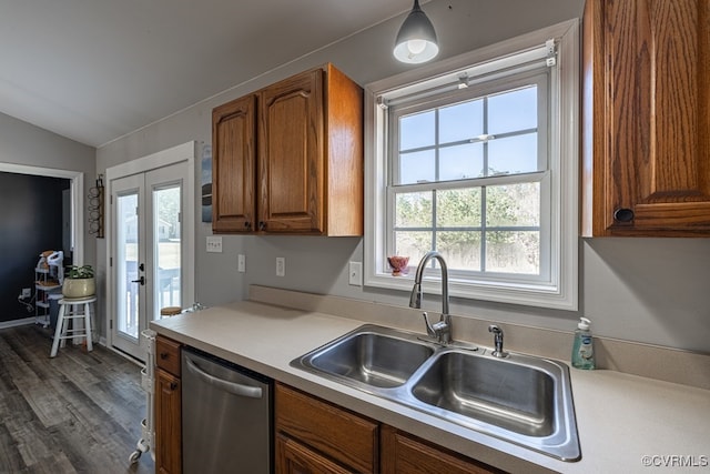 kitchen with vaulted ceiling, stainless steel dishwasher, a sink, and brown cabinets