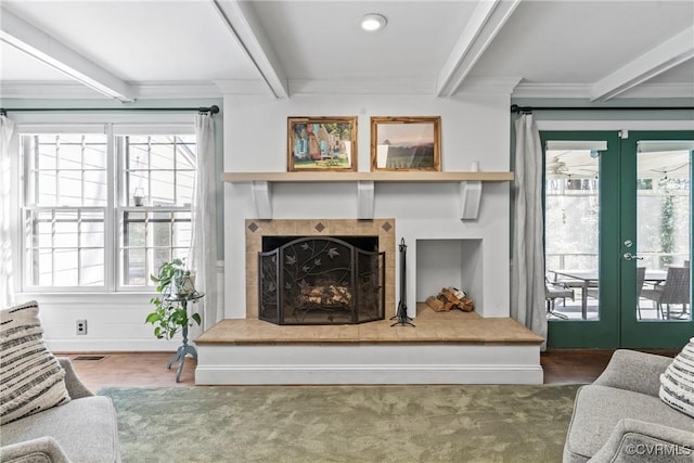 living room with a tile fireplace, plenty of natural light, beamed ceiling, and french doors