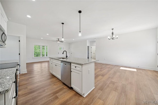 kitchen with open floor plan, light wood-style flooring, white cabinets, stainless steel appliances, and a sink