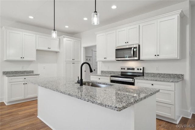 kitchen featuring wood finished floors, white cabinetry, stainless steel appliances, and a sink