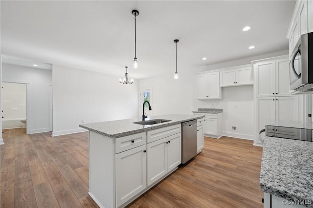 kitchen with a sink, light wood-style floors, appliances with stainless steel finishes, and white cabinetry