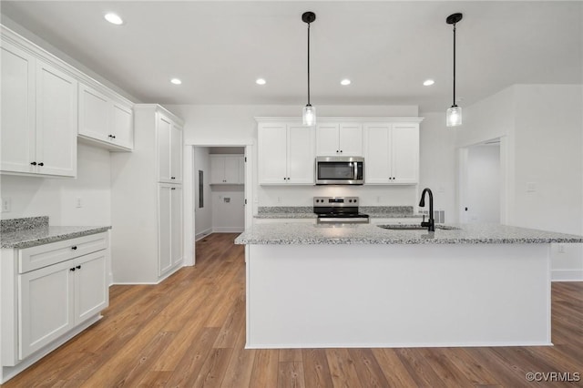 kitchen with a sink, stainless steel appliances, white cabinets, and light wood finished floors