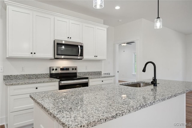 kitchen featuring an island with sink, a sink, light stone counters, stainless steel appliances, and white cabinets