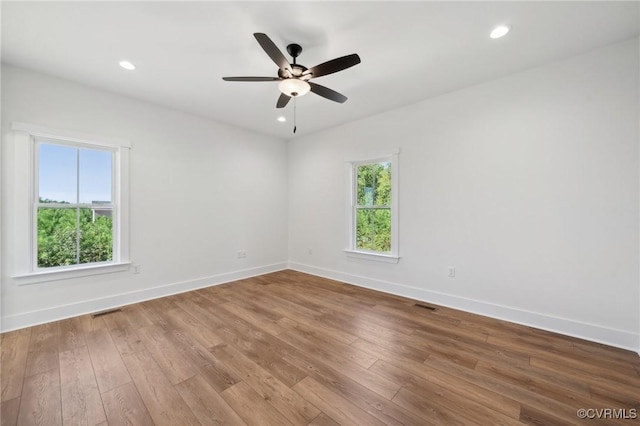 spare room featuring a wealth of natural light, baseboards, wood finished floors, and recessed lighting