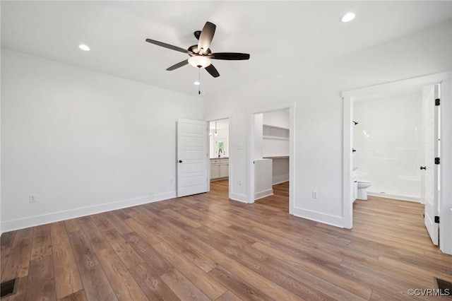 unfurnished bedroom with a spacious closet, recessed lighting, baseboards, and wood-type flooring