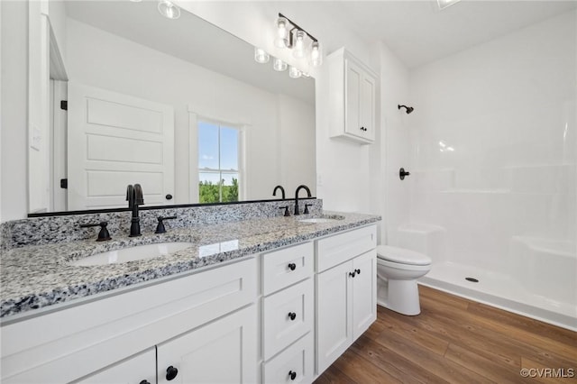 bathroom with wood finished floors, walk in shower, and a sink