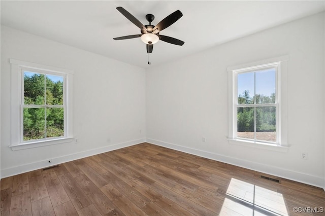 unfurnished room featuring visible vents, a ceiling fan, baseboards, and hardwood / wood-style floors