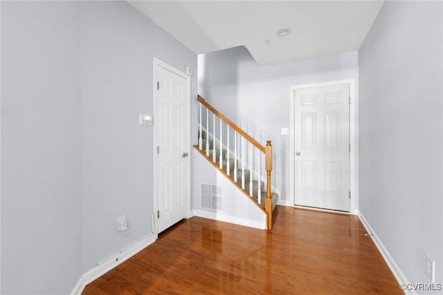 foyer entrance featuring visible vents, stairway, baseboards, and wood finished floors