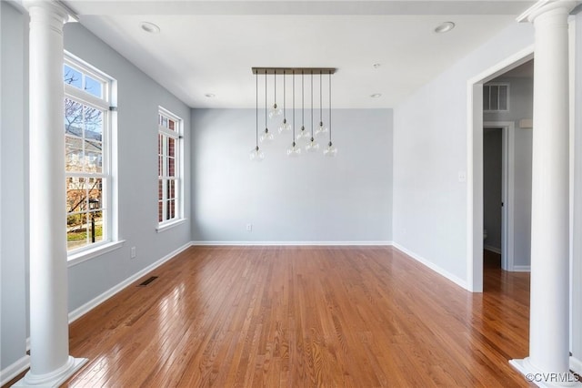 spare room featuring light wood-type flooring, decorative columns, baseboards, and visible vents