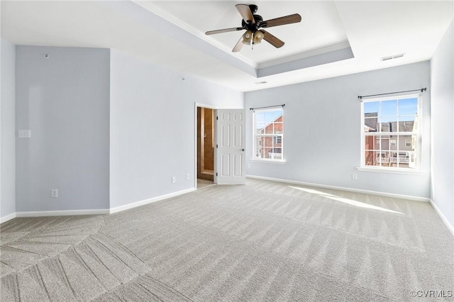 unfurnished room with baseboards, a raised ceiling, carpet floors, and crown molding