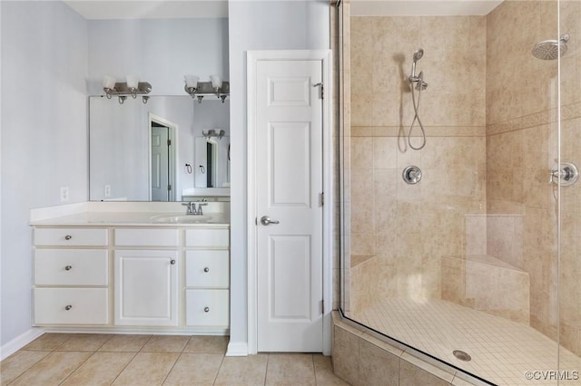 bathroom featuring tile patterned flooring, vanity, baseboards, and a tile shower