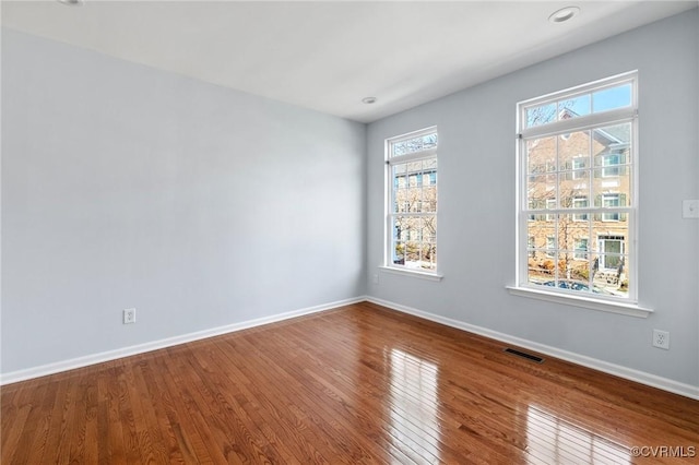 spare room featuring visible vents, baseboards, and hardwood / wood-style flooring